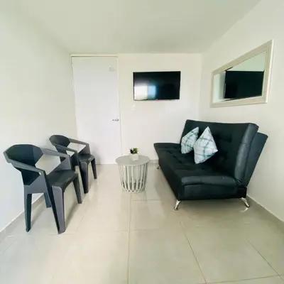 a living room with a black leather couch and chairs at Hermoso Apartamento en Coveñas en unidad residencial in Coveñas