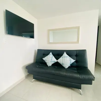 a black leather couch with two pillows on it at Hermoso Apartamento en Coveñas en unidad residencial in Coveñas
