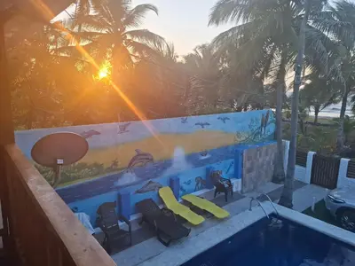 a swimming pool with two yellow chairs and the sunset at Cabaña frente al mar en moñitos, córdoba in Moñitos