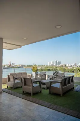a patio with chairs and tables and a view of the water at Suite con balcón cerca al centro Cartagena in Cartagena de Indias
