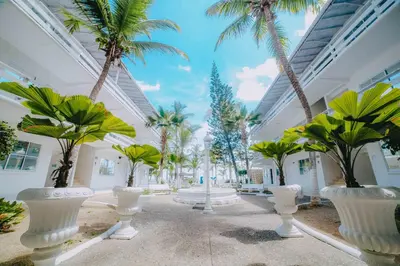 a courtyard with palm trees in white vases at Kpré Coveñas by Bernalo Hotels in Coveñas