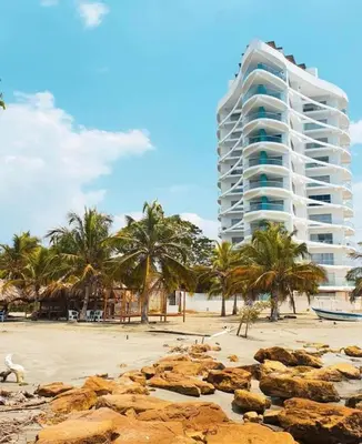 a building on the beach with palm trees and rocks at Magico Apartamento Frente al Mar 3 Habitaciones FB73 in Coveñas