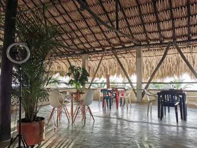 a restaurant with chairs and tables and a straw roof at Tata Lolo in Coveñas