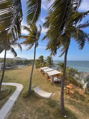 a group of tables and palm trees near the ocean at Vista Mare Beach House in Tierra Bomba