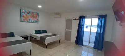 a room with two beds and a window with blue curtains at Hotel La Inmaculada in Soledad