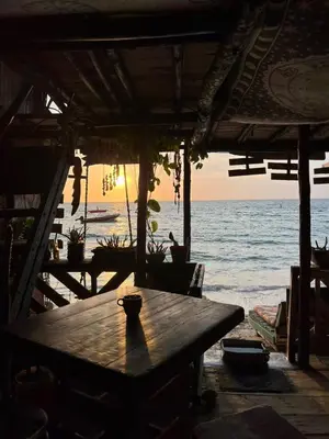 a wooden table on the beach with a view of the ocean at DespertArte espacio de Arte y Hospedaje in Playa Blanca