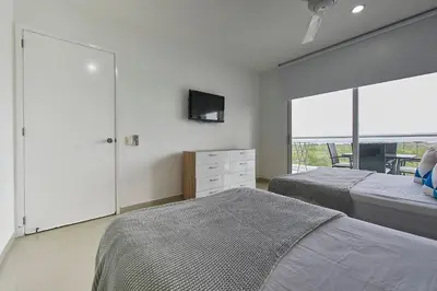 a bedroom with two beds and a tv on the wall at Morros Pelican Sunrise - Livin Colombia in Cartagena de Indias