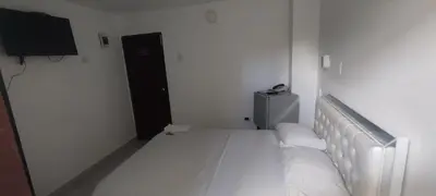 a white bedroom with a bed and a television at hotel interamericano in Barranquilla