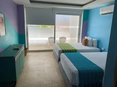 a hotel room with two beds and a balcony at Hotel Coco Beach by Croma in Cartagena de Indias