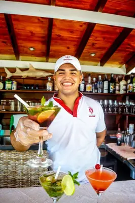 a man standing behind a bar holding a drink at Casa Cordoba Baru in Baru