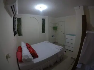 a white bedroom with a bed with red pillows at La casita de max y tim apt 201 in Cartagena de Indias