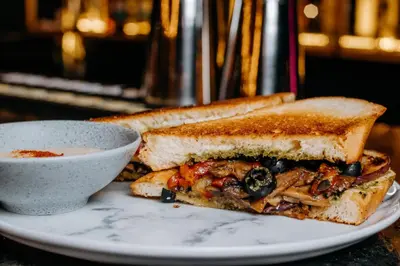 a sandwich on a plate next to a bowl of soup at San Felicin Hostel in Cartagena de Indias