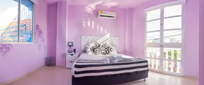 a bedroom with purple walls and a bed with towels on it at San Felicin Hostel in Cartagena de Indias