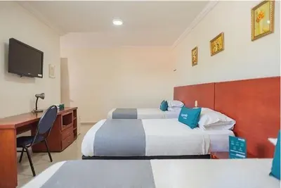 a hotel room with two beds and a desk and a television at Hotel Rivera Del Mar in Barranquilla