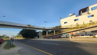 a bridge over a road with people walking down the street at Hospedaje Mi Fortaleza, Con Piscina, Parqueadero y estamos a 10 Minutos Caminando a Playa Dormida in Santa Marta