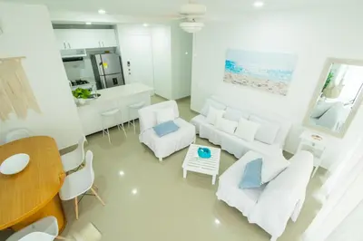 a living room with white furniture and a kitchen at Hermoso apartamento en la playa in Cartagena de Indias