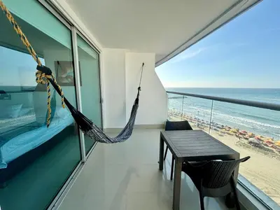 a hammock in a room with a view of the beach at Playa Cartagena Apartments in Cartagena de Indias