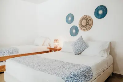 two beds in a room with white walls at Hotel Carey Beach Baru in Baru