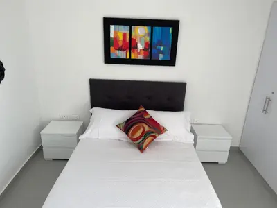 a bedroom with a white bed with two white night stands at Hermoso Apartamento, con vista al mar, en Cartagena de Indias, dos cuartos in Cartagena de Indias