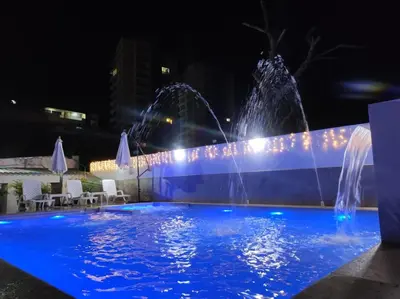 two water fountains in a pool at night at Apartamentos Villa Leonor in Coveñas