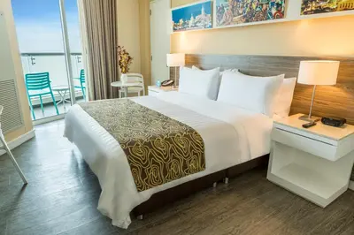 a hotel room with a large bed and a balcony at GHL Corales de Indias in Cartagena de Indias