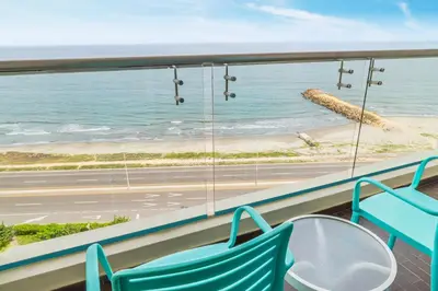 a balcony with two chairs and a view of the beach at GHL Corales de Indias in Cartagena de Indias