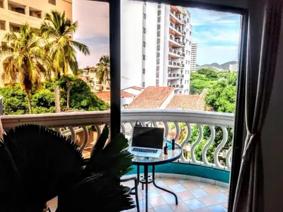 a room with a balcony with a laptop on a table at Amplio dúplex con playa y mall a una cuadra in Santa Marta