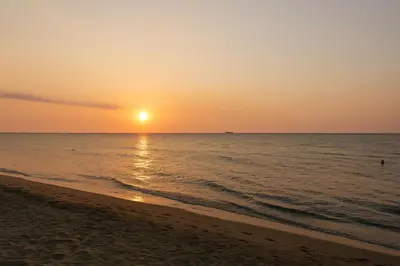 a beach with the sun setting over the ocean at A metros de las playas de Bello Horizonte y de Centro Comercial Zazue in Santa Marta