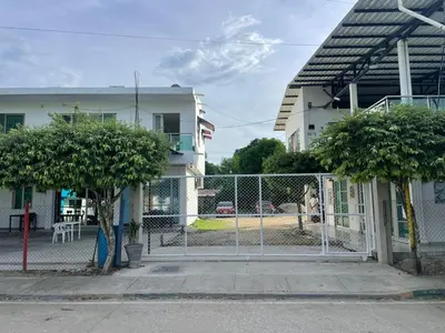 a fence with two trees in front of a building at Cabañas Melany in Coveñas