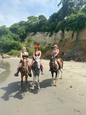 three women are riding horses on the beach at Casa Playa Arreboles in Cartagena de Indias