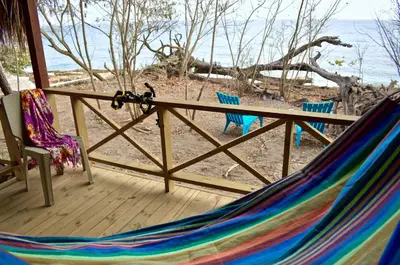 a hammock on a porch with a view of the beach at Centro Ubuntu in Isla Grande