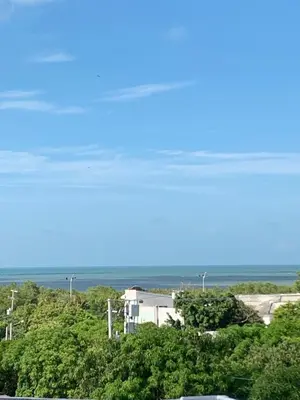 a building on a hill with trees and the ocean at ARMANI in Puerto Colombia