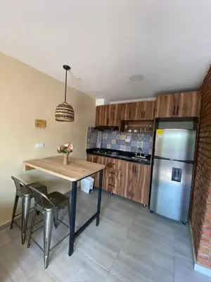 a kitchen with a table and a refrigerator at Apartaestudios - Casa Tamarindo in Aracataca