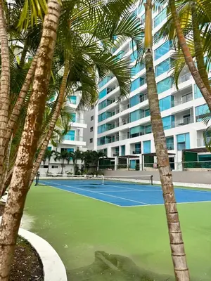 a tennis court with palm trees in front of a building at Apto- Condominio H Sonesta - Morros-salida a la playa - cerca Hotel Americas in Cartagena de Indias