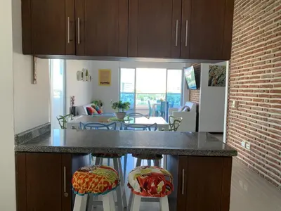 a kitchen with two bar stools and a living room at Hermoso y amplio apartamento en Cartagena de Indias in Cartagena de Indias
