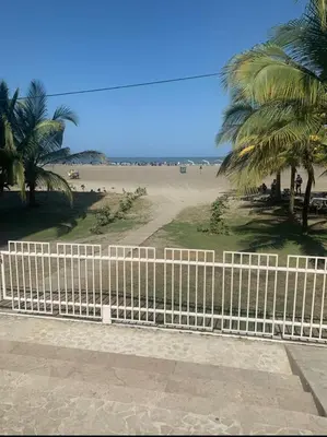 a white fence next to a beach with palm trees at Cartagena Genius Morros frente al mar in Cartagena de Indias
