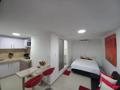 a white bedroom with a bed and a kitchen at La casita de max y tim apartaestudio 4to piso in Cartagena de Indias