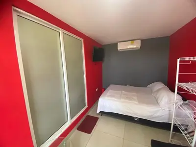 a small room with a bed and a red wall at La casita de max y tim apartaestudio 4to piso in Cartagena de Indias