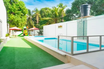 a swimming pool with a green lawn next to a house at ZABDI COVEÑAS in Coveñas