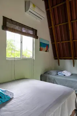 a bedroom with two beds and a window with a fan at Hostal Campomar in Santa Veronica
