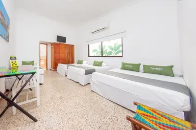 a room with three beds and a table and a desk at Hotel Ayenda Casa Cano 1805 in Cartagena de Indias