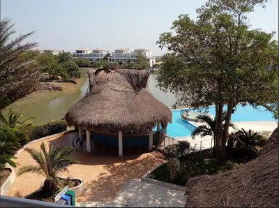 a resort with a swimming pool and a straw hut at Condominio Campestre Laguna Club Cartagena in Los Arrayanes