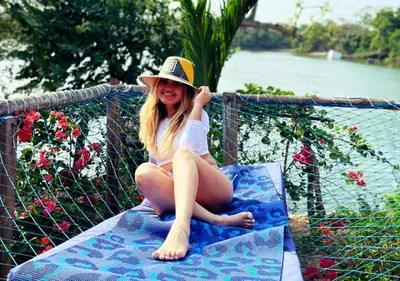 a woman in a hat sitting on a bench at Laguna Rosa Glamping in Coveñas