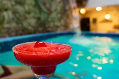 a drink with a cherry on top in front of a pool at Candilejo Hotel Boutique in Cartagena de Indias