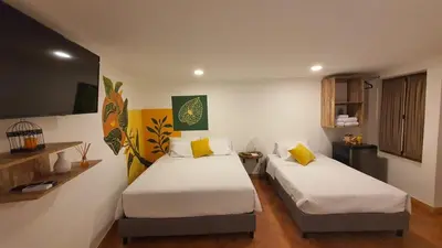 a bedroom with two beds and a tv on the wall at Candilejo Hotel Boutique in Cartagena de Indias