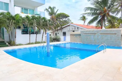 a swimming pool in front of a house with palm trees at Magico Apartamento Frente al Mar 2 Habitaciones B11A in Coveñas