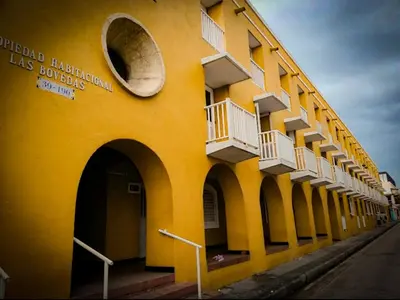 a yellow building with white balconies on a street at conjunto habitacional las bóvedas in Cartagena de Indias