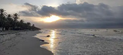 a beach with the sun setting on the horizon at El Viejo del Mar in San Bernardo del Viento