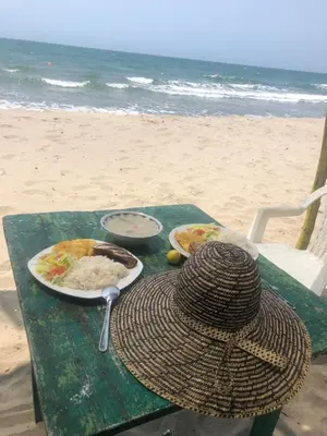 a table with plates of food and a hat on the beach at Jamadis in Tolú