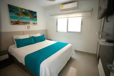 a bedroom with a large bed with blue pillows at Hotel Poblado Coveñas in Coveñas